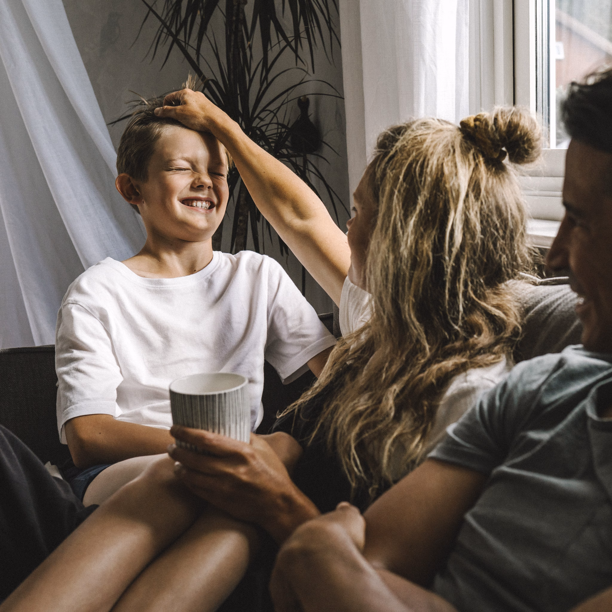 Eltern und Sohn sitzen auf Sofa und lachen.