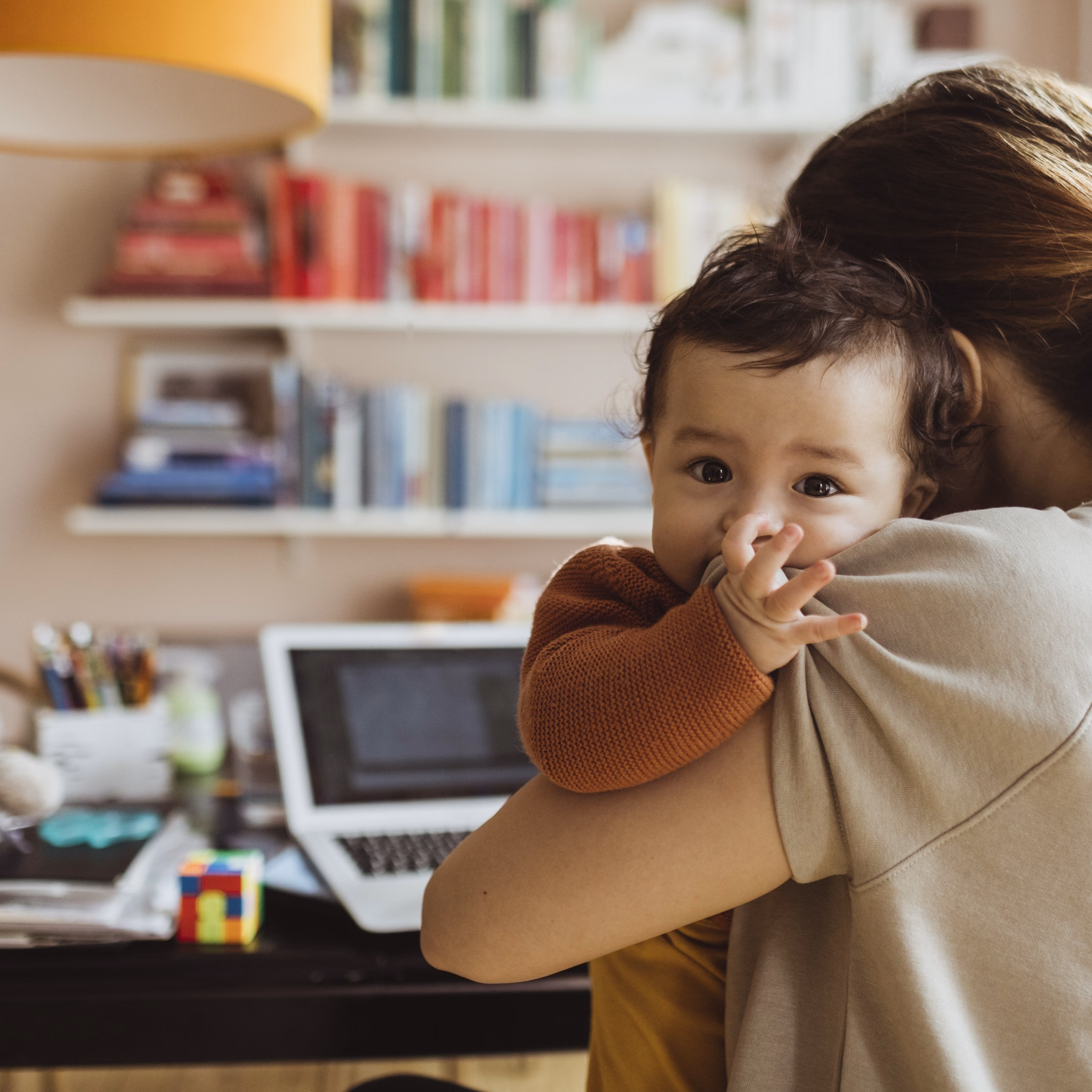 Mutter hat Baby im Arm und arbeitet.