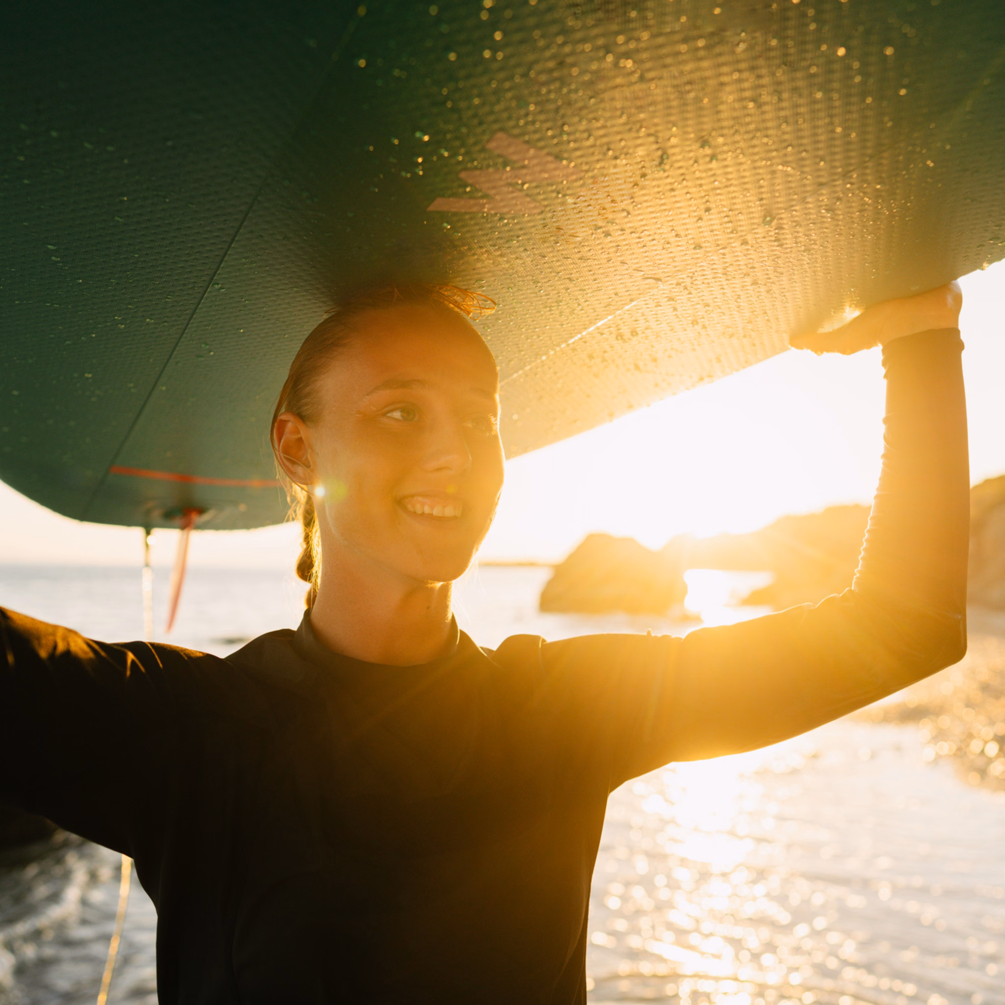 Jujnge Frau trägt ihr Surfbrett über dem Kopf am Strand
