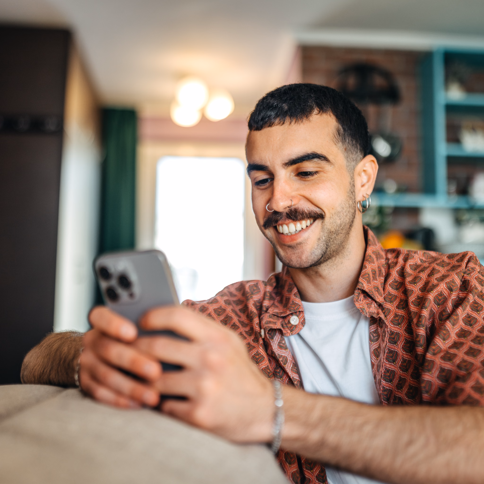 Mann sitzt auf dem Sofa und benutzt sein Handy
