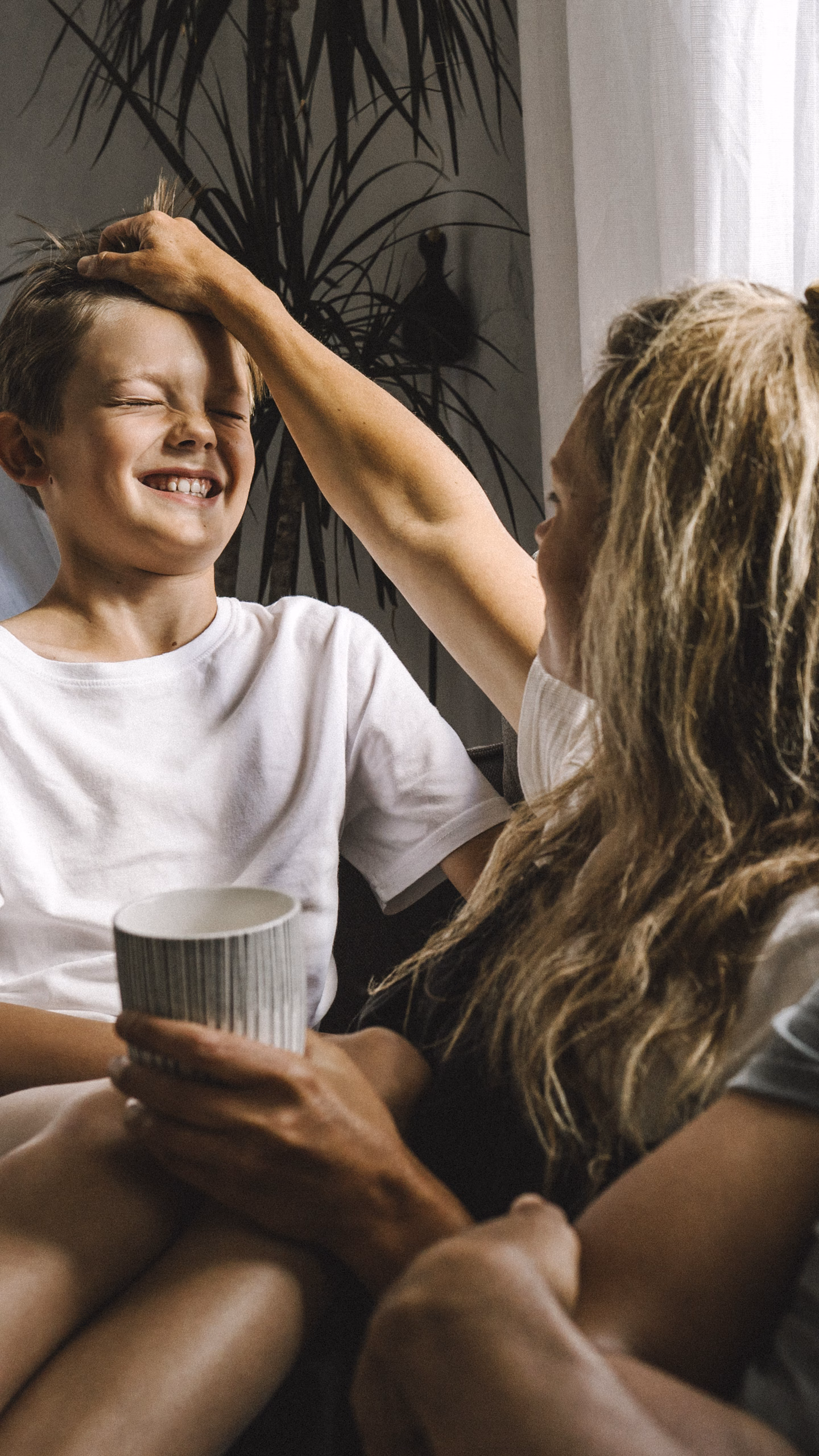 Eltern und Sohn sitzen auf Sofa und lachen.